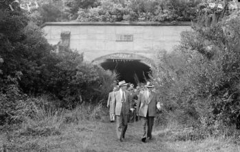 Group of men outside the Wainuiomata tunnel. Evening post (Newspaper. 1865-2002) :Photographic negatives and prints of the Evening Post newspaper. Ref: 114/280/02-G. Alexander Turnbull Library, Wellington, New Zealand. /records/23139125