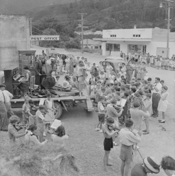 Circa 1959 Children's orchestra playing outside Post Office, Wainuiomata, Lower Hutt. Evening post (Newspaper. 1865-2002) :Photographic negatives and prints of the Evening Post newspaper. Ref: EP/1955/2759-F. Alexander Turnbull Library, Wellington, New Zealand. https://natlib.govt.nz/records/22301620