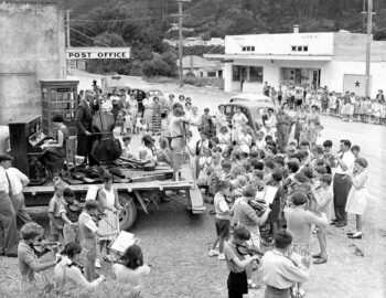 Circa 1959 Children's orchestra playing outside Post Office, Wainuiomata, Lower Hutt. Evening post (Newspaper. 1865-2002) :Photographic negatives and prints of the Evening Post newspaper. Ref: EP/1955/2759-F. Alexander Turnbull Library, Wellington, New Zealand. https://natlib.govt.nz/records/22301620